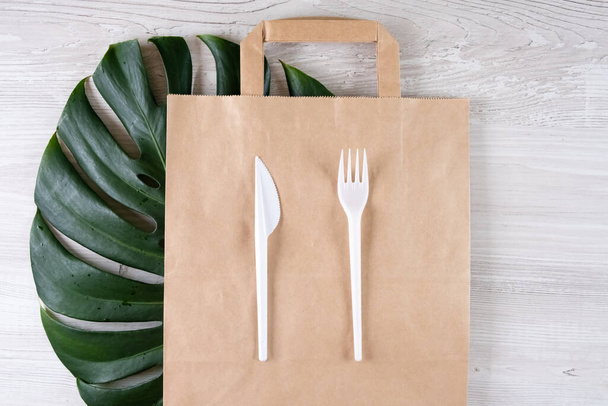 plastic fork, knife on paper bag. Eco-friendly food packaging and cotton eco bags on gray background with copy space. Carering of nature and recycling concept. containers for catering and street fast - Фото, зображення