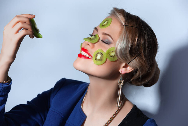 Fashion photo of woman posing with slices of kiwi on her face - Φωτογραφία, εικόνα