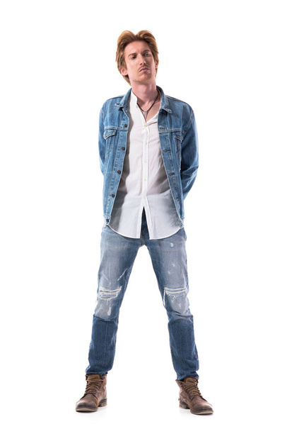 Stylish young male fashion model with red hair in jeans looking away with hands on back. Full body isolated on white background. - Valokuva, kuva