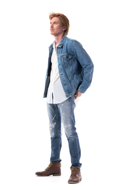 Stylish young redhead man in jeans looking up watching at attention. Full body isolated on white background. - Foto, immagini