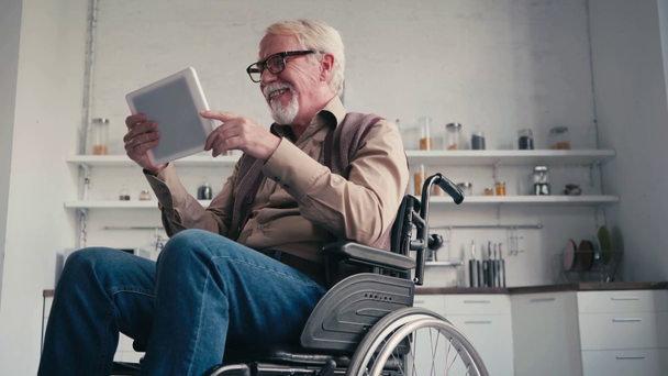 Χαμογελώντας συνταξιούχος με αναπηρία σε αναπηρική καρέκλα μιλώντας κατά τη διάρκεια βιντεοκλήσης στο σπίτι - Πλάνα, βίντεο