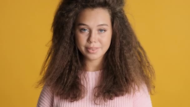 Portret van aantrekkelijke brunette mollig meisje vol vertrouwen op zoek in camera geïsoleerd op gele achtergrond - Video