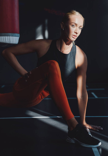 Un boxeur féminin sérieux s'échauffe dans un club de sport sombre - Photo, image