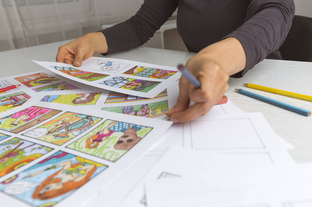 An animator painter draws a color storyboard for a comic book or movie. An illustrator seated at his desk creates a storyboard for a cartoon. - Photo, Image