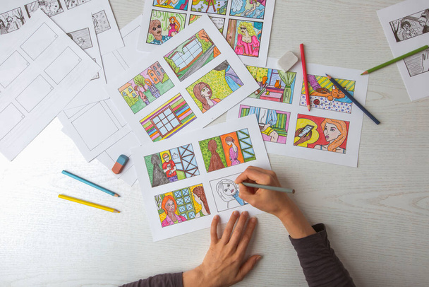 Um pintor de animador desenha um storyboard colorido para uma história em quadrinhos ou filme. Um ilustrador sentado em sua mesa cria um storyboard para um desenho animado. - Foto, Imagem