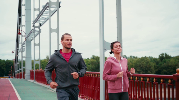 Paar atletische lopers met smartwatches op de brug, slow motion - Video