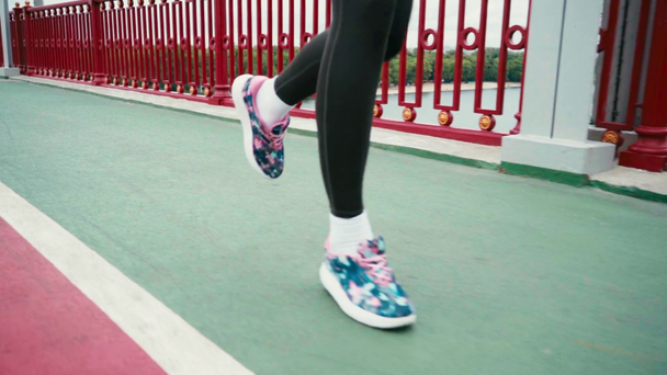 Περικοπή άποψη της γυναίκας σε sneakers τρέχει κατά μήκος του δρόμου στη γέφυρα, αργή κίνηση  - Πλάνα, βίντεο