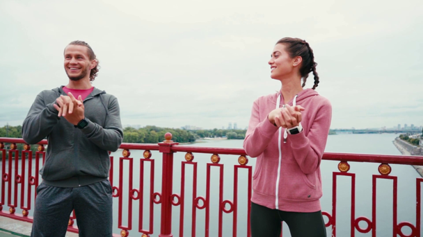 Μπροστά όψη του χαμογελαστού ζευγαριού σε αθλητικά ρούχα ζέσταμα με τη φύση στο παρασκήνιο - Πλάνα, βίντεο