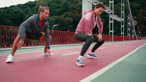 Man and woman in sportswear doing lunges on bridge with nature on background - Footage, Video