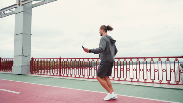 corde Sportsman sauter sur le pont avec la nature en arrière-plan, au ralenti - Séquence, vidéo