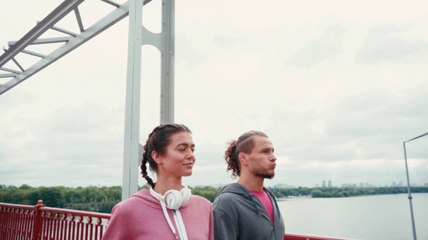Пара в спортивной одежде прогулка по мосту с природой на заднем плане, замедленная съемка - Кадры, видео