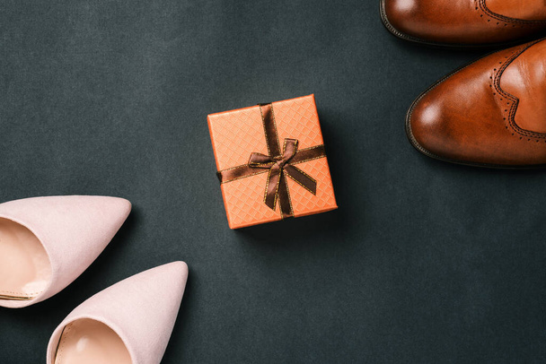 Sapatos femininos e femininos e uma caixa de presente com uma fita em um fundo preto. Acessórios elegantes e elegantes. Venda e entrega de sapatos - Foto, Imagem