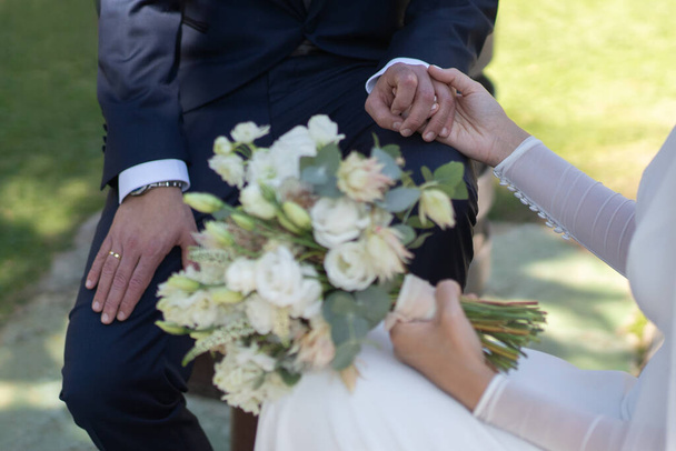 mariée en costume blanc tient de jolis bouquets de fleurs avec son marié - Photo, image