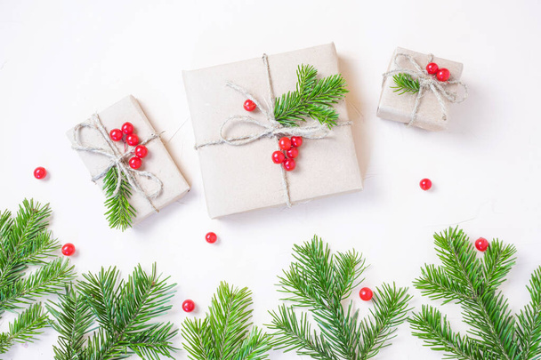 Natale eco flat lay: regali avvolti in carta artigianale, rami di abete rosso e bacche rosse come decorazione. Concetto di sostenibilità. - Foto, immagini