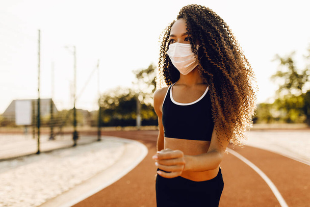 athletic african american woman in medical protective mask on her face, jogging outdoors, fitness, people and healthy lifestyle - Photo, Image