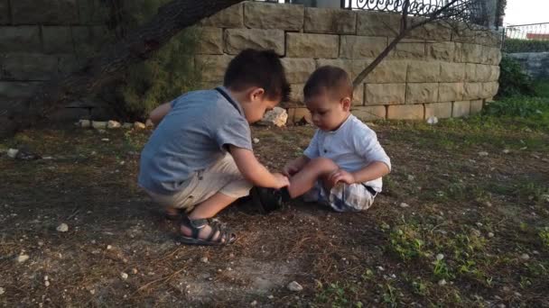 Cute 4 years old helping his brother to clean the knee after he felt down. Siblings taking care of each other - Footage, Video