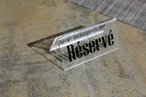 Plastic plaquette met de inscriptie Reserve op het is op een lege tafel.  - Foto, afbeelding
