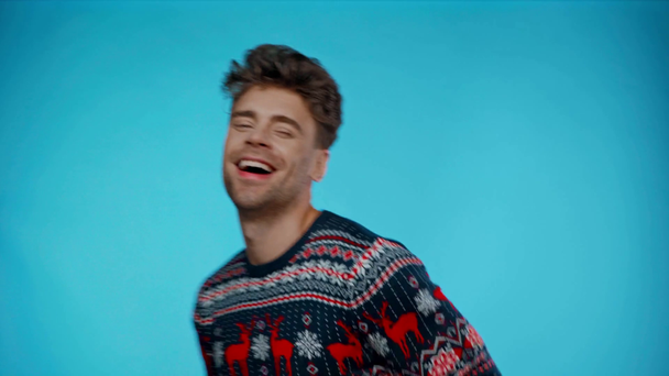 Feliz hombre adulto joven en suéter bailando y señalando con los dedos en azul - Metraje, vídeo