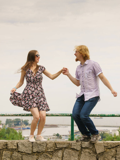 Joyful couple having fun outdoor. Young man and woman dancing jumping together during date. - Фото, изображение