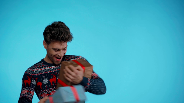Emocionado joven adulto hombre la captura de regalos en azul - Metraje, vídeo