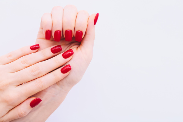 Vrouwelijke handen met rode manicure op lichtgrijze achtergrond - Foto, afbeelding