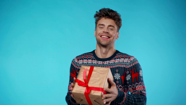 Feliz hombre adulto joven sosteniendo caja de regalo y mostrando sí gesto en azul - Metraje, vídeo