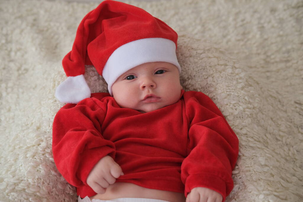 Baby im Weihnachtsmannkostüm auf weißem Hintergrund. Weihnachtskind mit Weihnachtsmütze - Foto, Bild