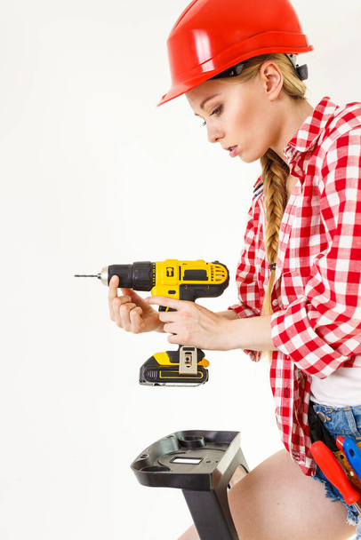 Young determinated woman adjusting drill doing home renovation. Female construction worker having driller tool drilling wall. - Photo, Image