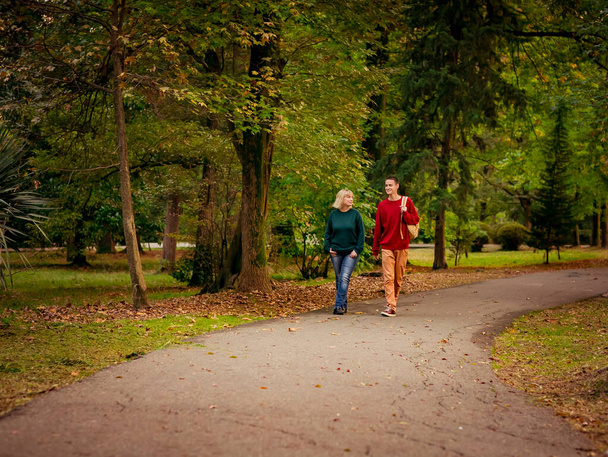 Krásná žena, blondýna, středního věku, s dospívajícím synem procházejícím se v parku, krásný podzimní den - Fotografie, Obrázek