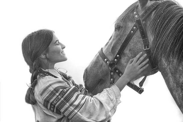 Young attractive white woman in noble clothes stroking a horse. - Photo, Image
