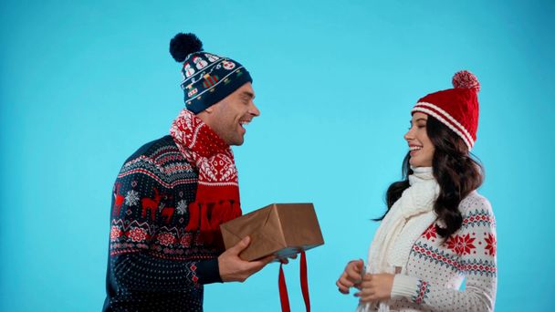Hombre excitado en bufanda y sombrero apertura caja de regalo y abrazar a la mujer en azul - Metraje, vídeo