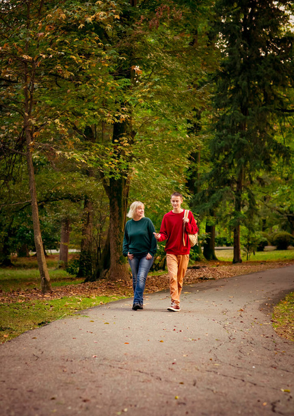 Beautiful woman,blonde,middle-aged,with a teenage son walking in the Park,a beautiful autumn day - Foto, Imagen