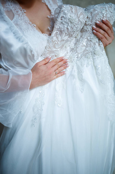 η νύφη κρατά στα χέρια της ένα όμορφο νυφικό - Φωτογραφία, εικόνα
