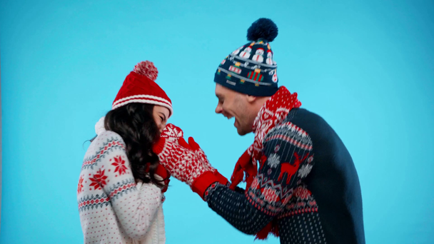 Happy couple freezing and rubbing hands, warming up on blue - Footage, Video