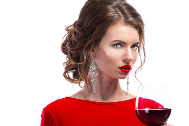 Woman with makeup, hairstyle waering red dress posing with glass of vine over white background, isolate - Foto, Imagem