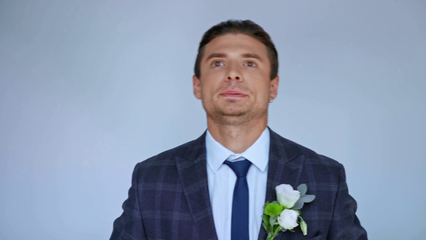 worried groom touching suit with boutonniere isolated on grey - Footage, Video