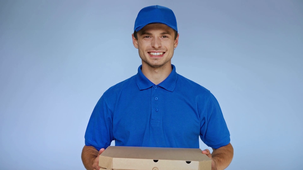 šťastný donáška muž mluví, zatímco drží karton krabice od pizzy na šedé - Záběry, video