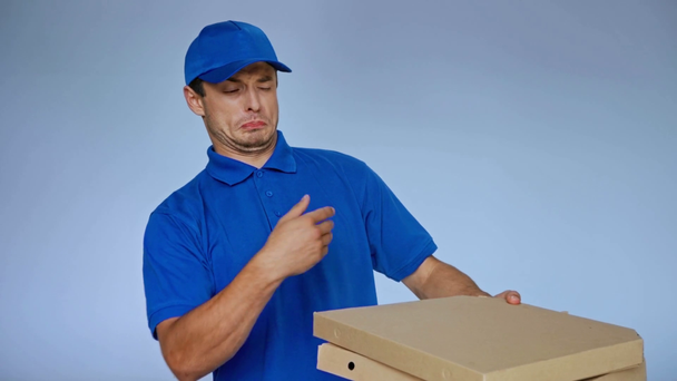 homem de entrega descontente segurando pizza fedorenta em caixas em cinza - Filmagem, Vídeo