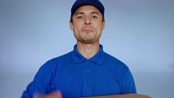 boldog futár integetett kezét és tartotta pizza dobozok szürke - Felvétel, videó