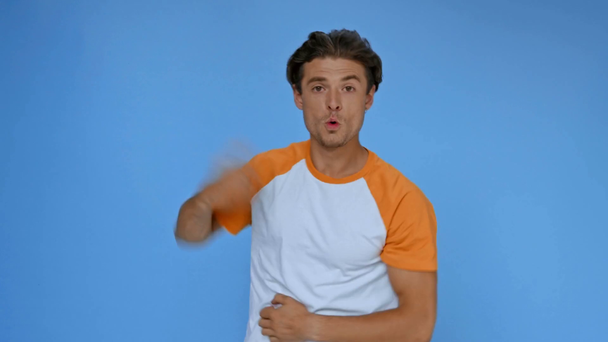 Χαρούμενος άντρας με μπλουζάκι που χορεύει απομονωμένος στο μπλε - Πλάνα, βίντεο
