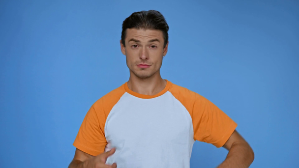 alegre hombre en camiseta mostrando ok signo aislado en azul - Metraje, vídeo