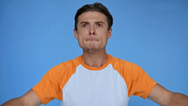man in t-shirt smelling pleasant fragrance isolated on blue - Footage, Video