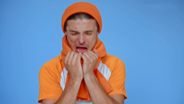 beteg ember kalapban és sál köhögés elszigetelt kék - Felvétel, videó
