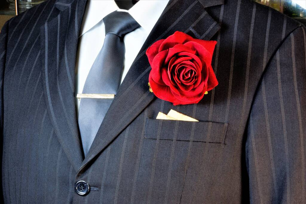Heren pak en boutonniere rode roos - accessoire decoratie van mannen jas, zakelijke kleding. Ze dragen het op bruiloften, gala 's en belangrijke evenementen. - Foto, afbeelding