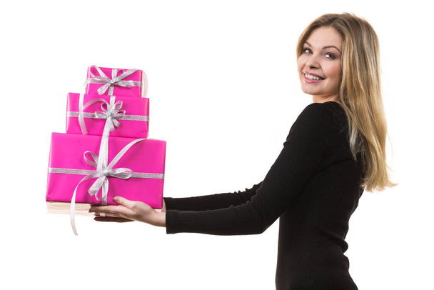 People celebrating xmas love and happiness concept. Cheerful blonde girl holding presents pile of pink gift boxes, side view - Fotografie, Obrázek