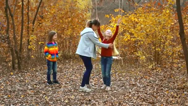 Mam zwaait kinderen op een touwschommel. Gelukkige familie in de natuur in de herfst. twee mooie meisjes zijn gelukkig en lachen. kleurrijke gele achtergrond. - Video