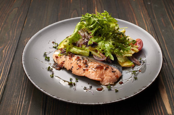 Salad with avocado and salmon, on a wooden background - Photo, Image
