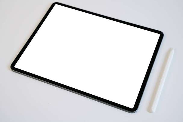 Mockup di tablet e matita digitale con schermo bianco vuoto su tavolo bianco. - Foto, immagini