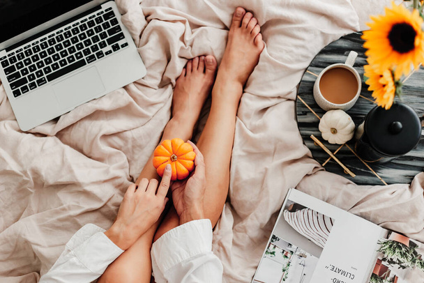 Woman is enjoying coffee in the bed. Working on the laptop. Sunflower arrangement. Bedroom vibe. Autumn season. Feeling home comfortable. Enjoying little things. Fall colors and mood. Work at home. - Фото, зображення