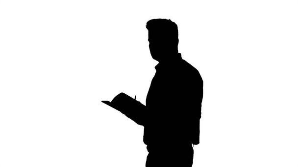 Silhouette Male manager formal dressed holding notepad walking and making notes looking around. - Φωτογραφία, εικόνα